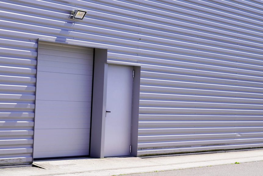Grey metal roll-down shutters on vertical profiled sheeting gray building fire exit door in commercial industrial unit